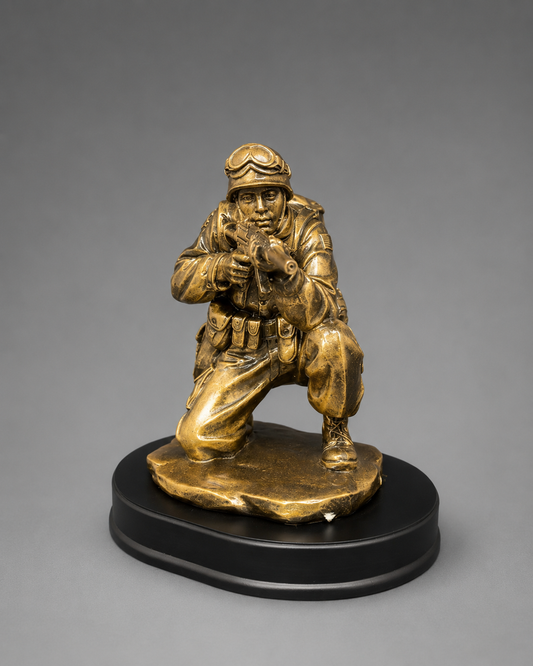 Front view of a bronze-finish kneeling soldier figurine aiming a rifle, displayed on a black oval base against a neutral gray background.