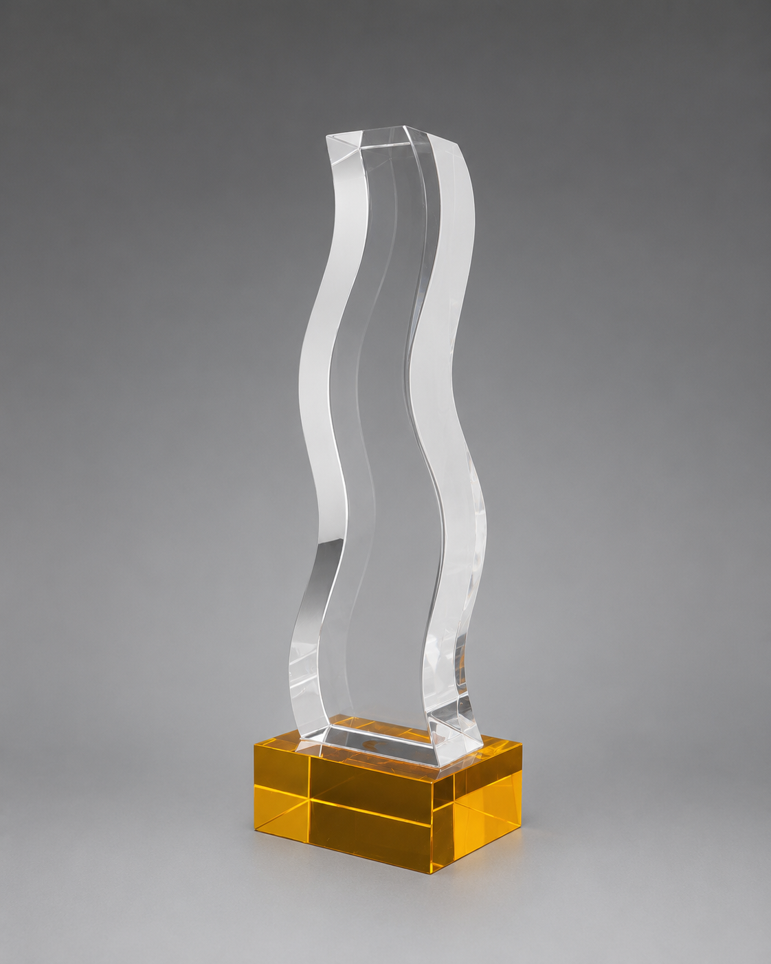 Clear wave-shaped crystal recognition piece on an amber-gold rectangular base, photographed at a three-quarter angle.