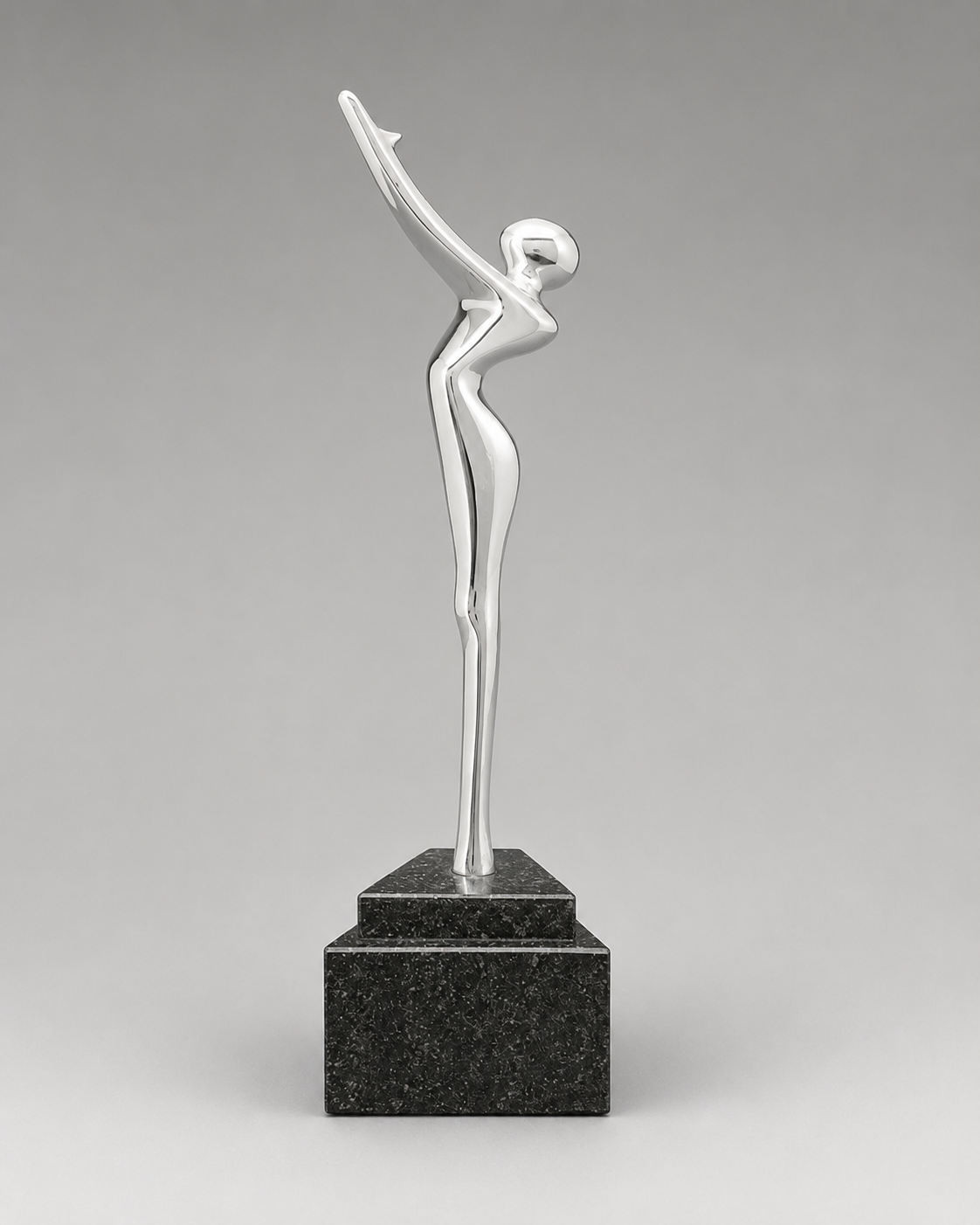 Front view of a polished silver abstract human figure reaching upward on a stepped black marble base against a neutral gray background.