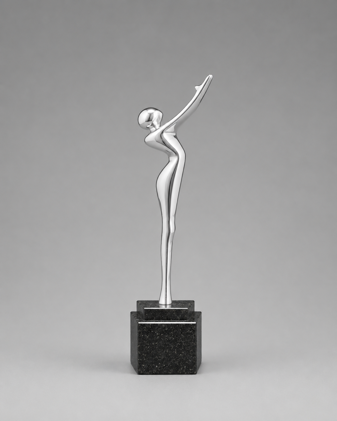 Opposite angled view of a sleek silver reaching figure displayed on a tiered black base against a gray studio background.