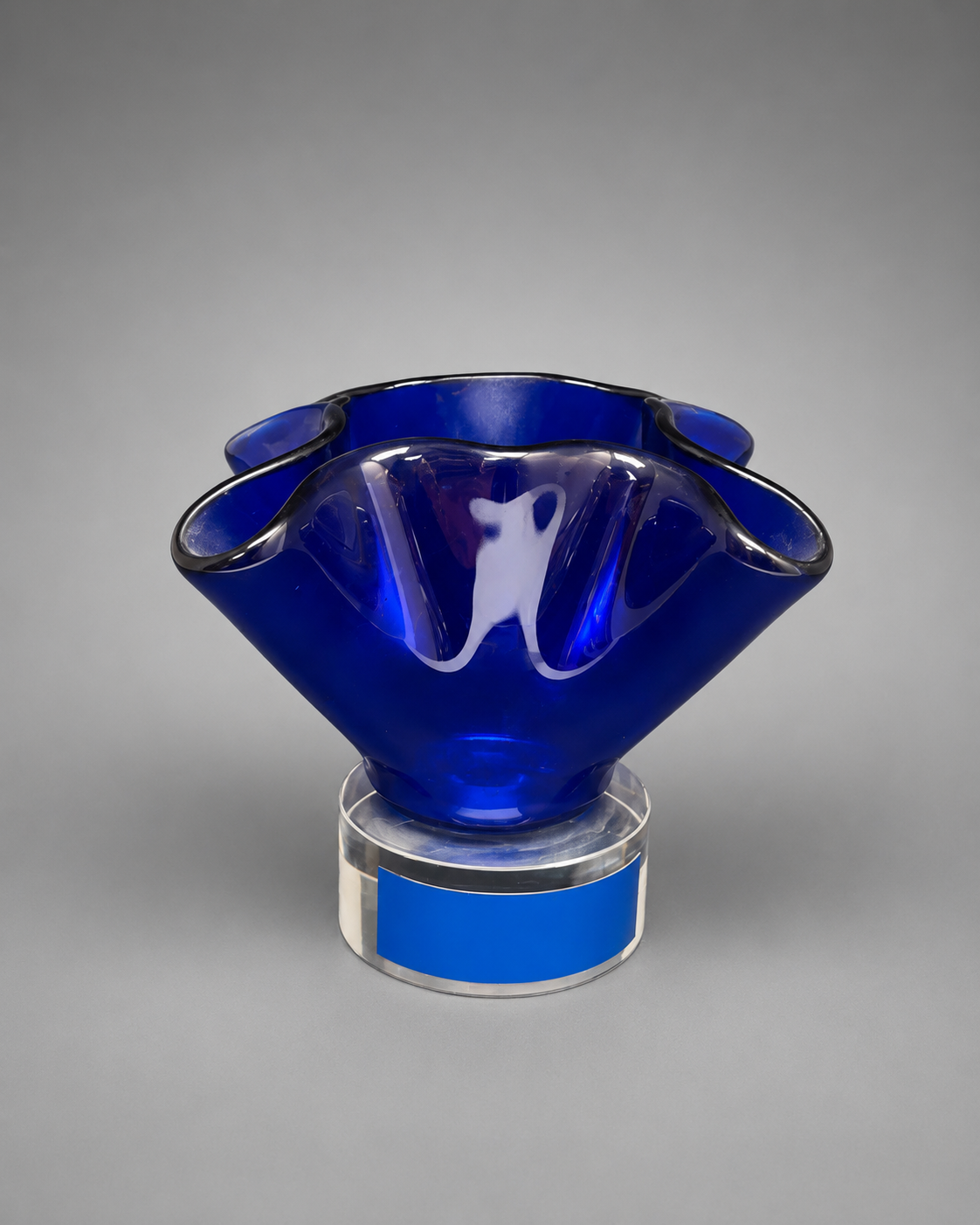Front view of a blue bloomed glass vase on clear stand. 