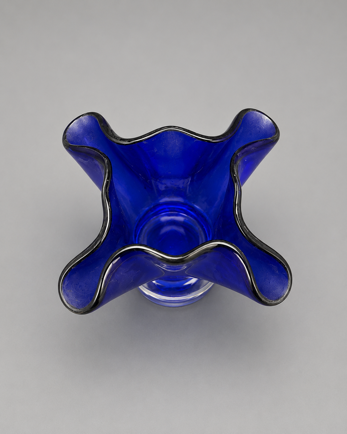 top view of a blue bloomed glass vase on clear stand. 