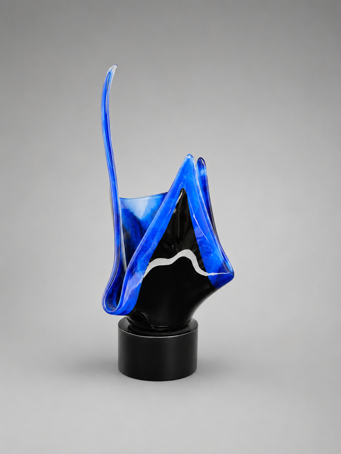 Side view of blue and black exotic flame designed vase on a black stand.