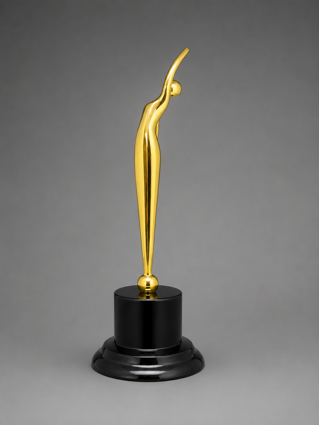 Modern gold abstract achievement award featuring an elegant raised-arm figure on a glossy black pedestal base with a neutral gray background.