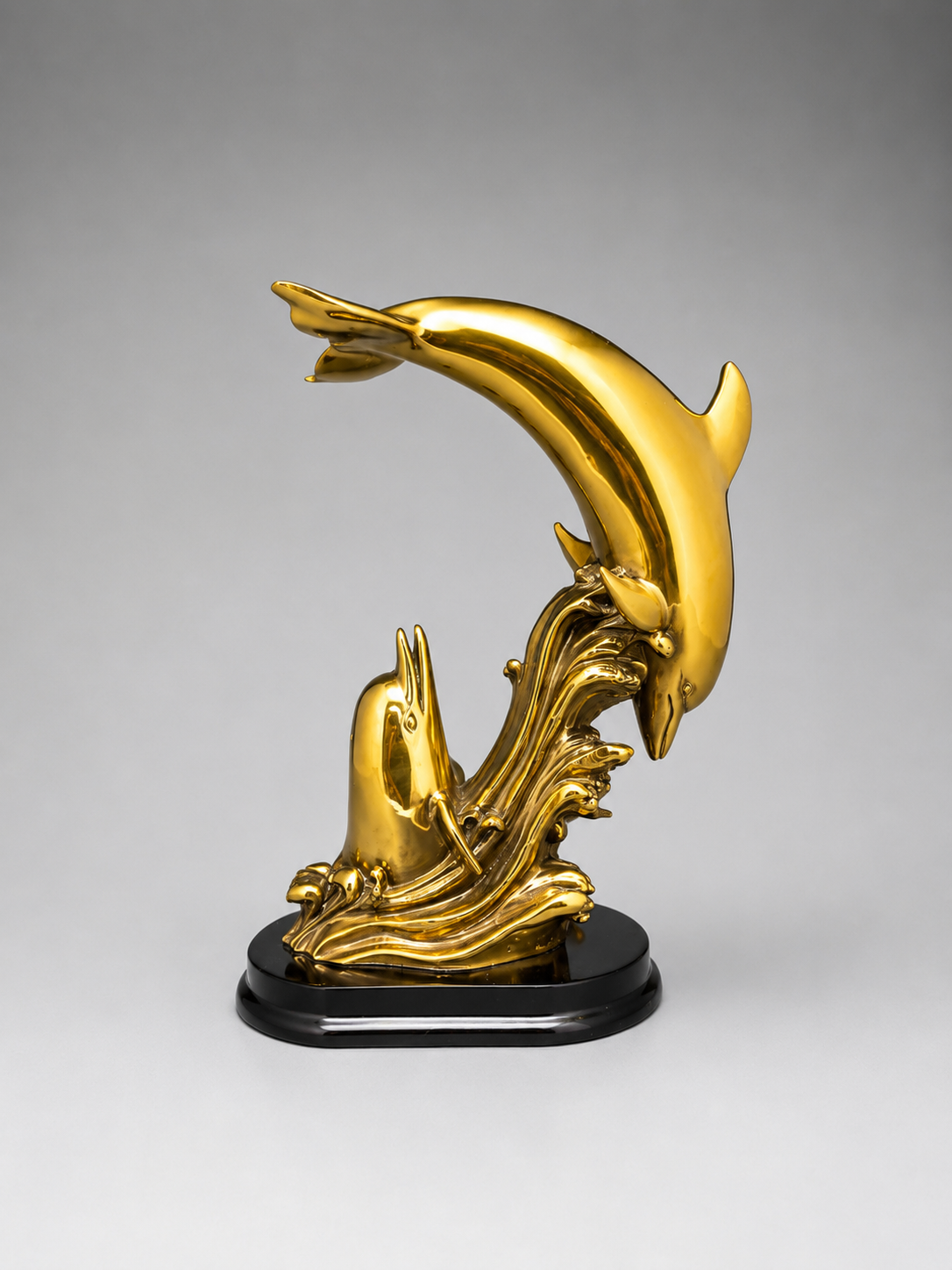 Gold dolphin sculpture on a gray background. Back view