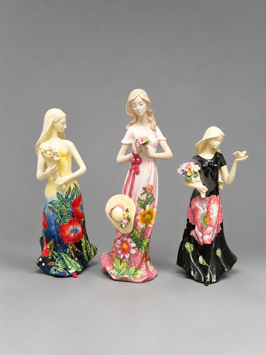 Three colorful figurines of women with floral designs on a gray background