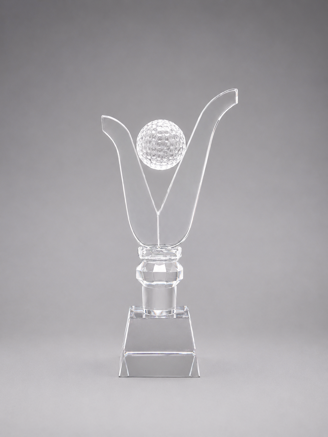 Clear glass trophy with a golf ball on a gray background