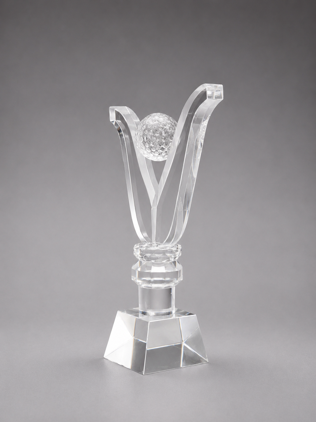 Clear glass trophy with a golf ball design on a gray background