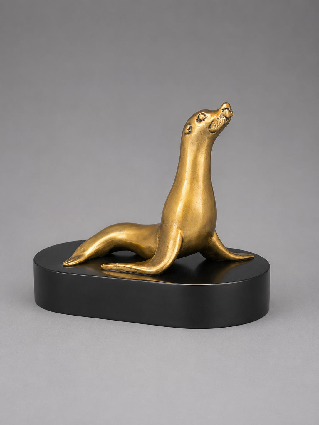 Bronze seal sculpture on a black base against a gray background