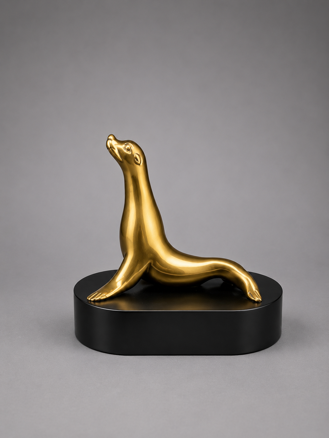 Bronze seal sculpture on a black base against a gray background