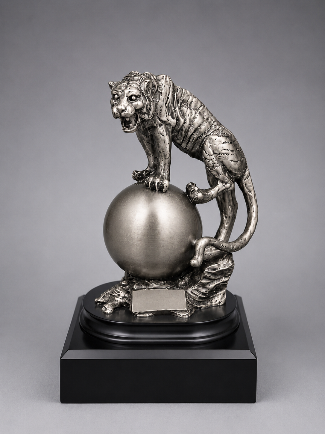 silver statue of a tiger on a sphere with a gray background