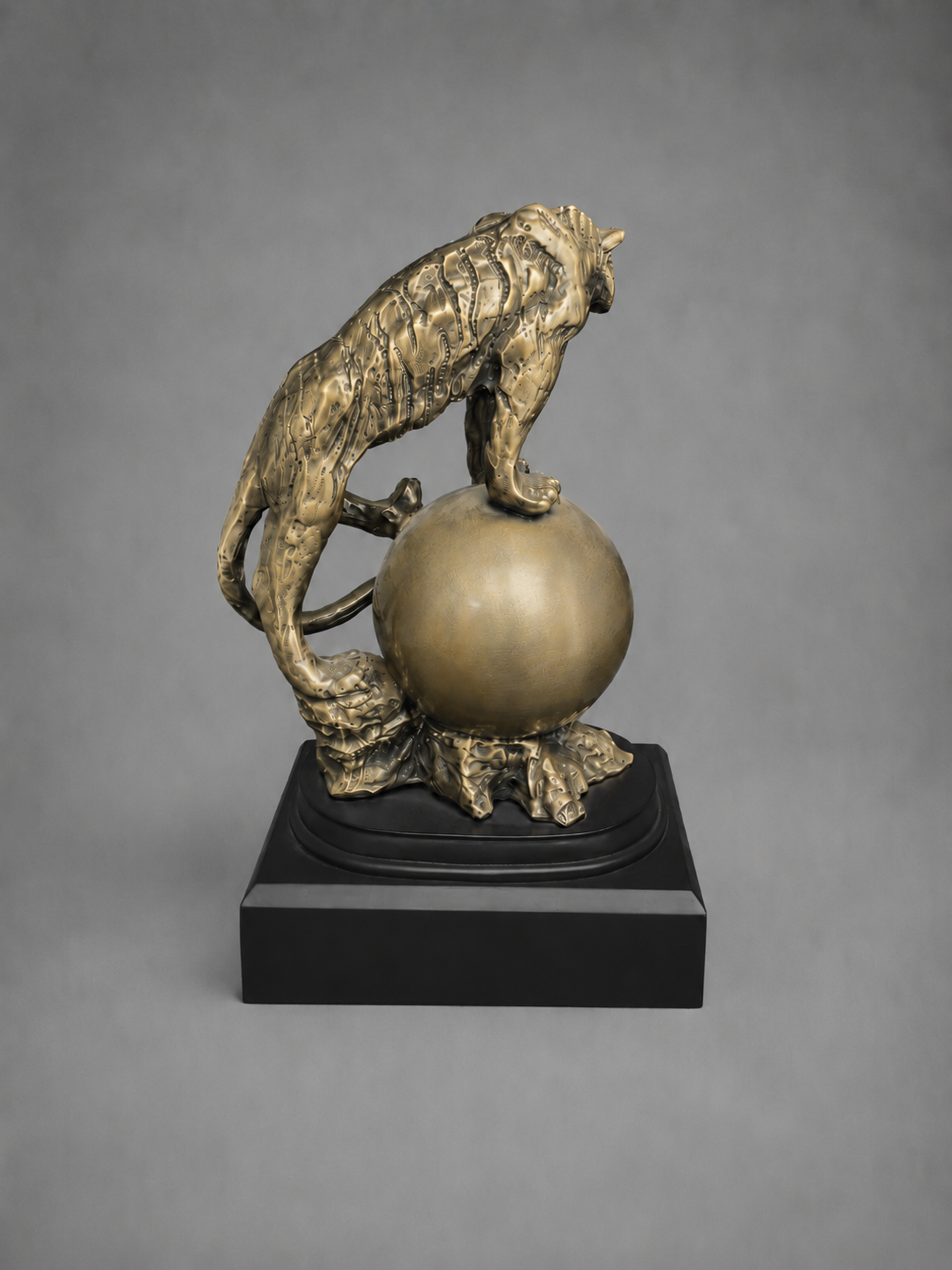 Bronze sculpture of a tiger on a sphere against a gray background