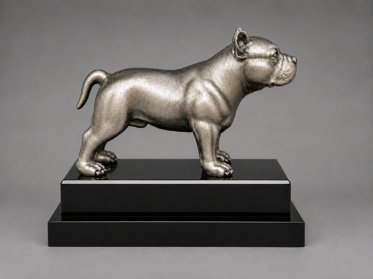 silverstatue of a dog on a black base against a gray background
