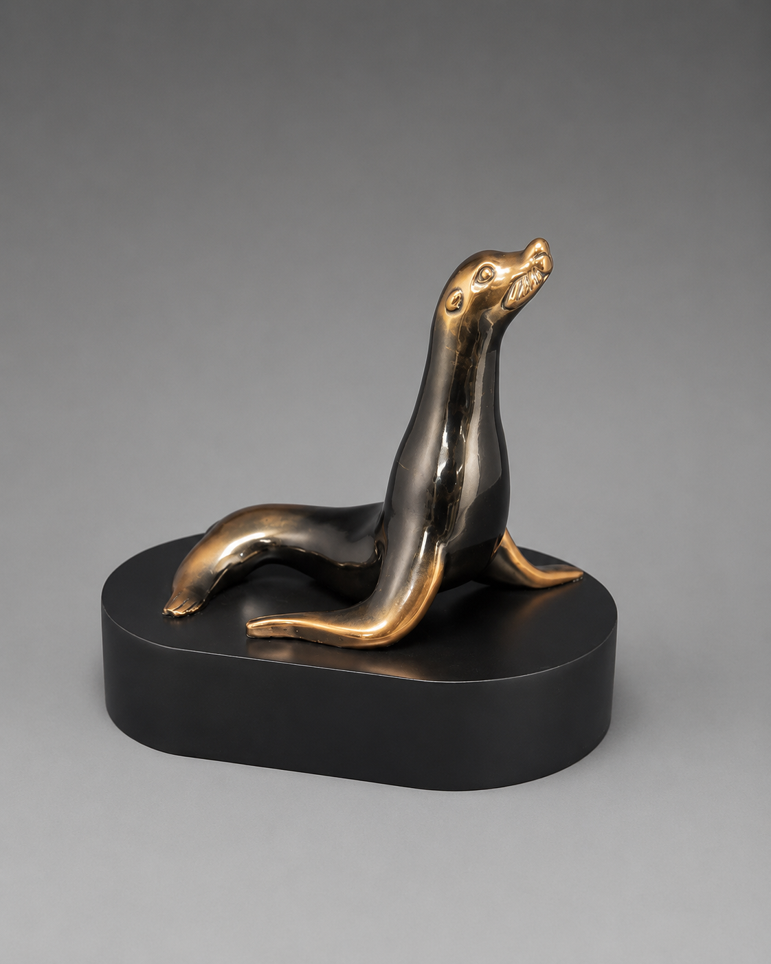Bronze seal sculpture on a black base against a gray background