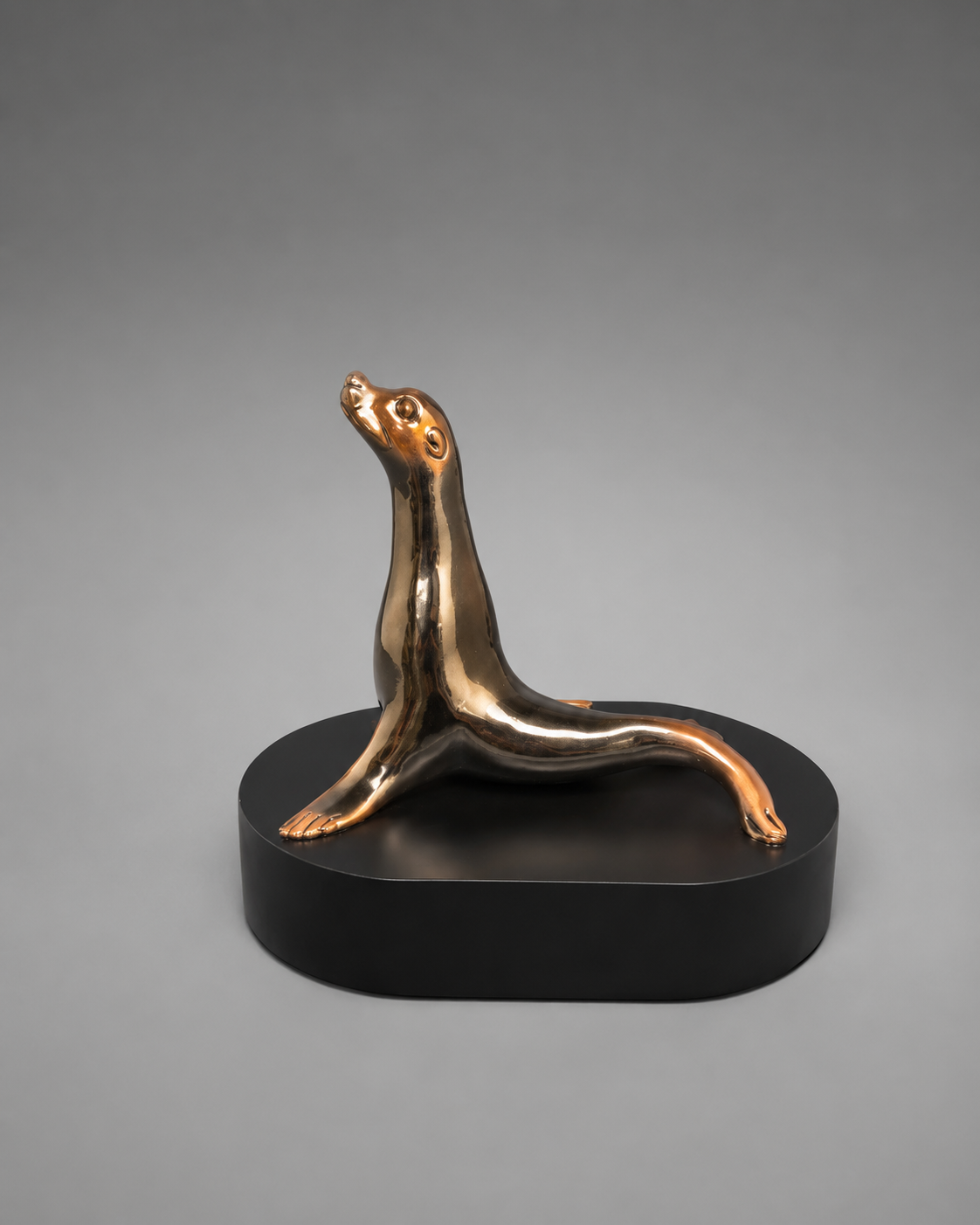 Bronze seal sculpture on a black base against a gray background