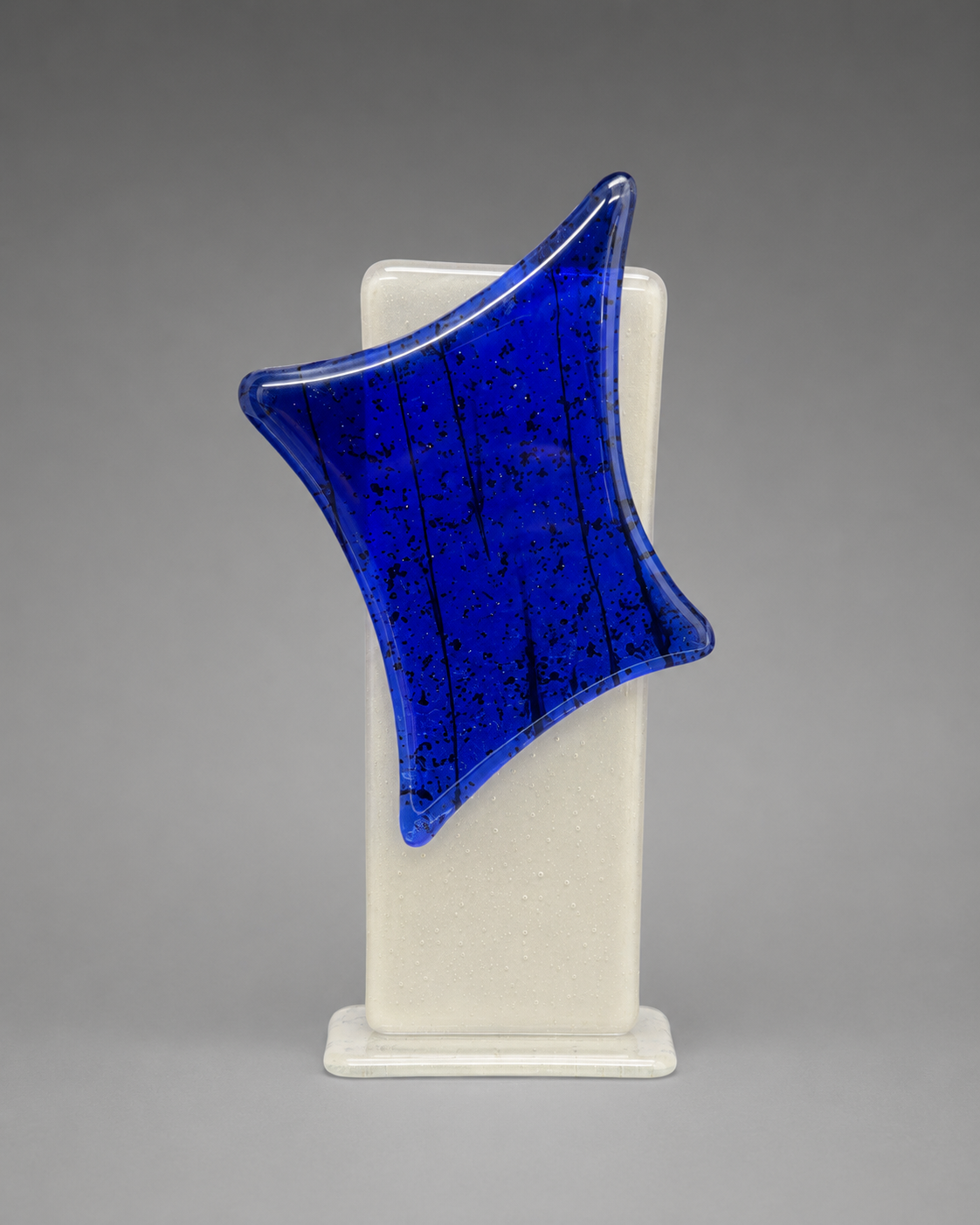 Blue glass sculpture on a white base against a gray background