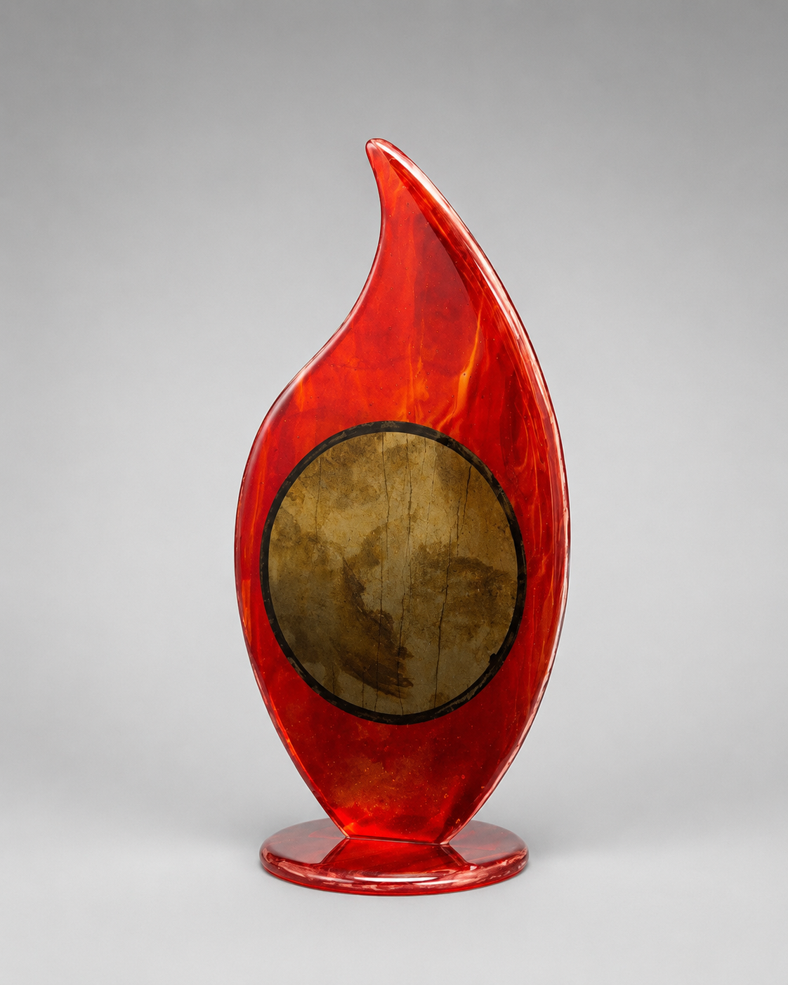 Red glass sculpture with a circular center on a gray background