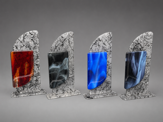 Four decorative glass art pieces with white and black marbled bases and vertical colored inserts, shown on a neutral gray background. The inserts are colored in amber-red, black, bright blue, and dark navy.