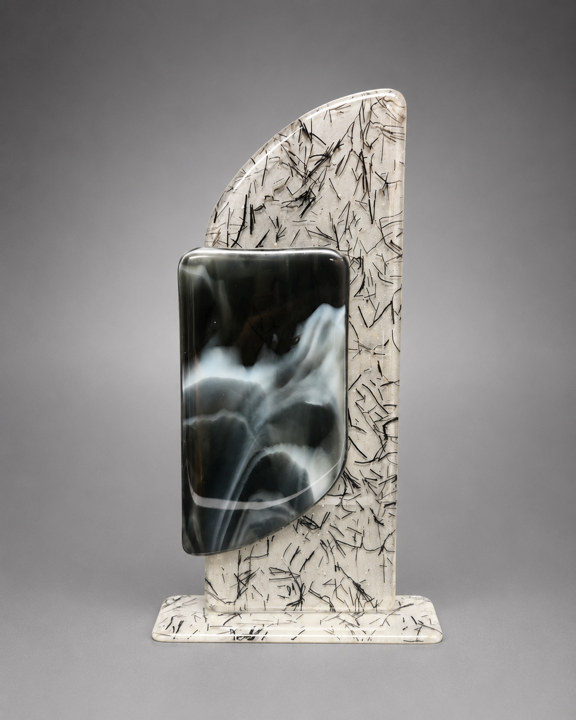 A decorative glass plaque featuring a vertical cream-colored base with fine black crystalline markings, a matching back panel, and a central glossy black and white marbled panel, photographed against a neutral gray gradient background.
