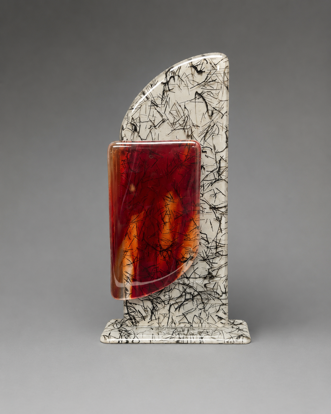 A modern glass plaque with a vertical white and black crackled base and a rectangular amber-red glass insert, shown on a neutral gray background.
